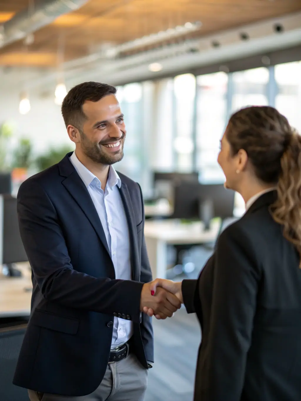A young man confidently shaking hands with a customer, symbolizing the first sales milestone in the Betta program.